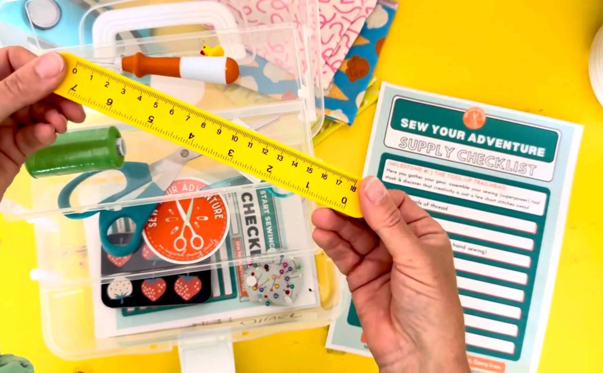 Flat lay of sewing supplies, measuring tape, sewing notions in clear box.