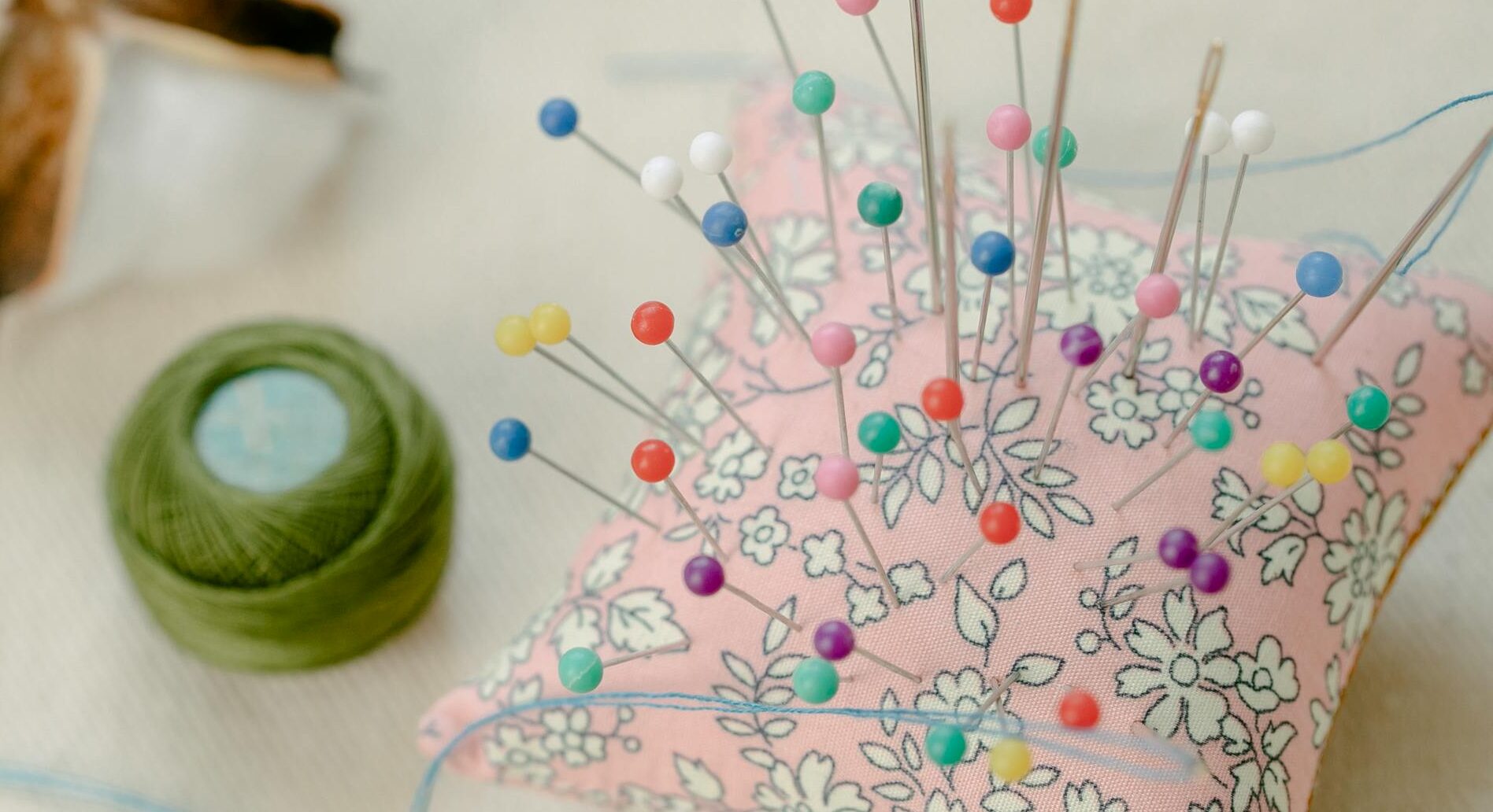 Colorful pins and threads on a sewing workspace, perfect for crafting inspiration.